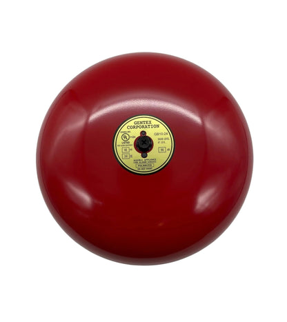 Gentex GB10-24 fire alarm bell in white, mounted on wall, with metal casing and mounting bracket for fire safety alert system